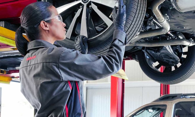 Nissan Service Technician working on tire with a gauge