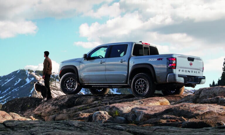 2023 Nissan Frontier parked in mountains with hiker and dog