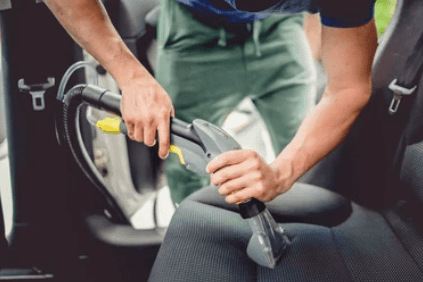 man provides car detailing services to interior of a vehicle.