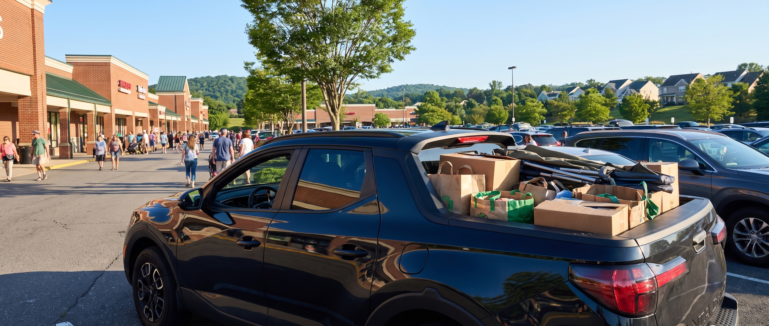 A Hyundai Santa Cruz parked in front of a bustling shopping center on a bright Tennessee afternoon, cargo bed loaded with shopping bags, outdoor gear, and boxes, with a suburban Nashville backdrop