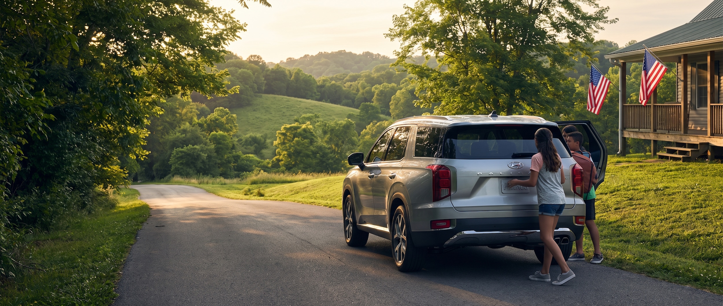 A silver or blue Hyundai SUV parked on a tree-lined road in Middle Tennessee, late-afternoon summer light, American flags visible in the background, lush green hills, suggesting a holiday road trip departure.