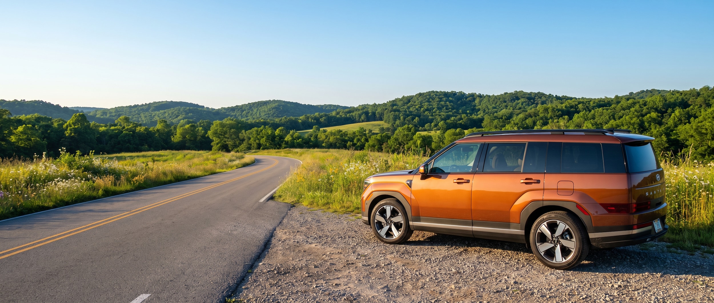 A 2026 Hyundai Santa Fe Hybrid in a warm metallic color parked on a scenic two-lane road through Middle Tennessee rolling hills in summer, green foliage in the background, clear blue sky, with a sense of a weekend getaway in progress