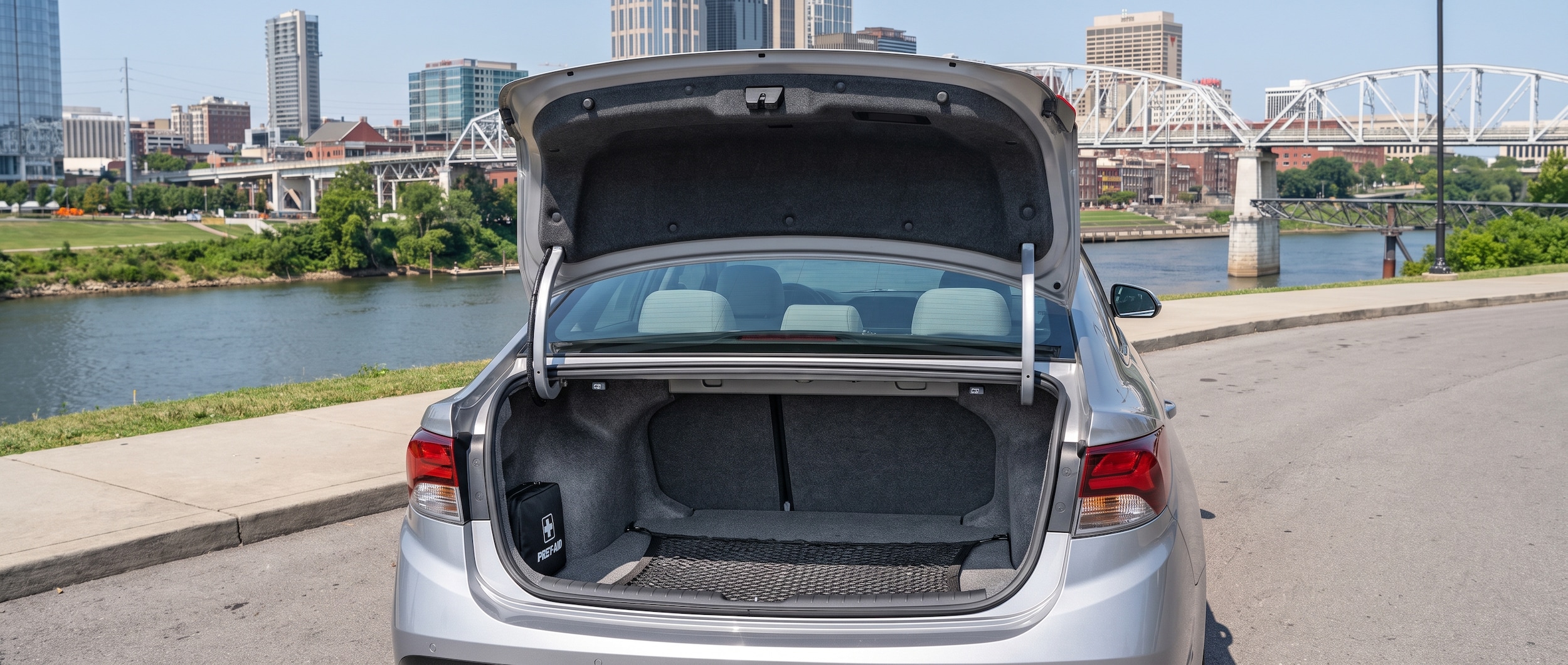 A 2026 Hyundai Sonata Hybrid in silver parked on a Nashville street near the Cumberland River waterfront on a bright summer afternoon, trunk open to reveal the full cargo area interior