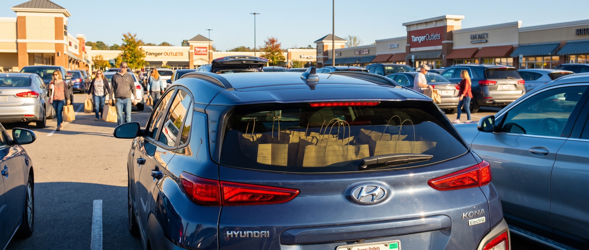 A Hyundai Kona Electric parked at Tanger Outlets Nashville with shopping bags visible in the rear cargo area, showcasing the blend of eco-friendly driving and retail therapy on a sunny weekend afternoon