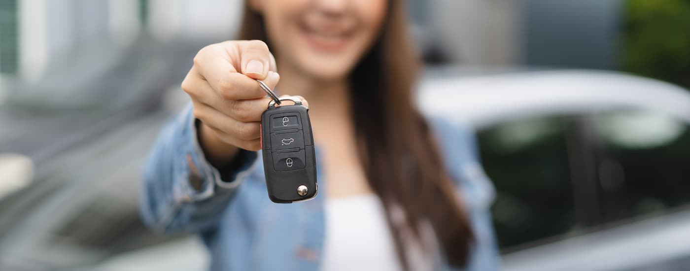 Smiling woman holding out a car key.