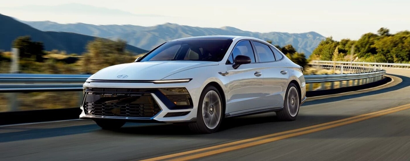 A white 2024 Hyundai Sonata N-Line is driving to a Hyundai dealer near Charlotte.
