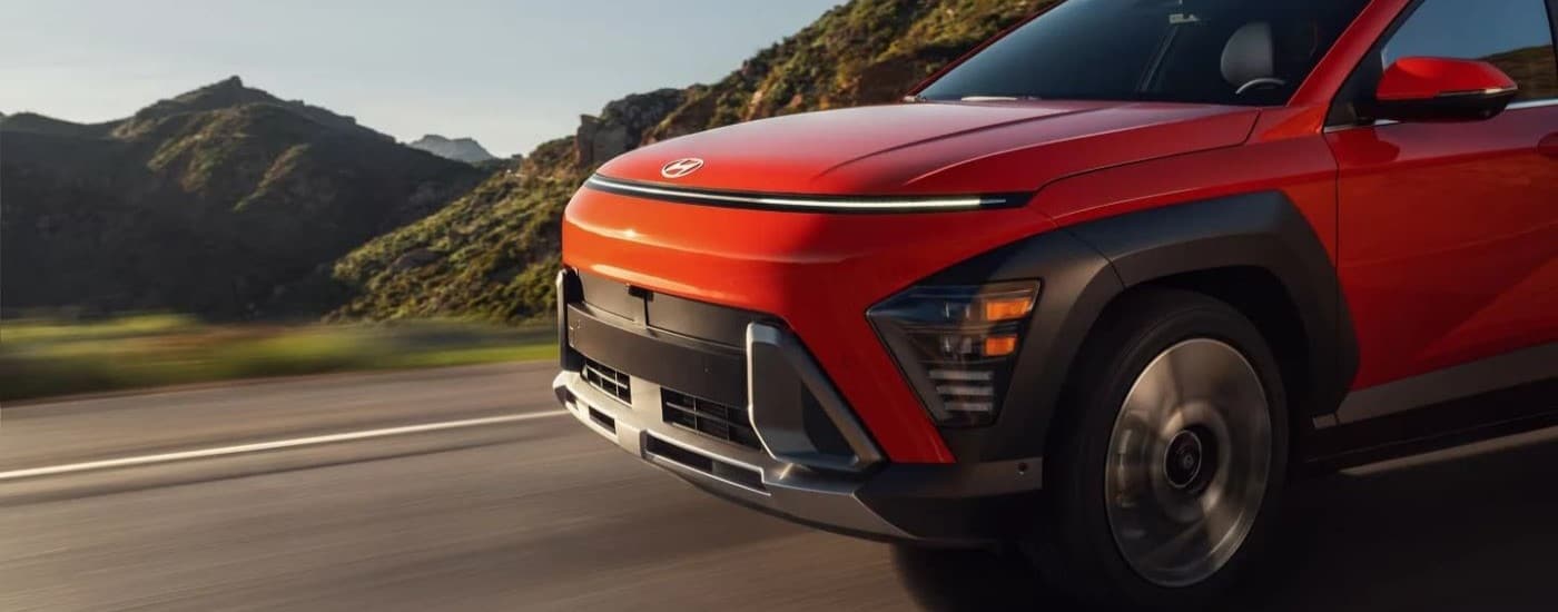 Close-up on the front of a 2026 Hyundai Kona driving down a road.