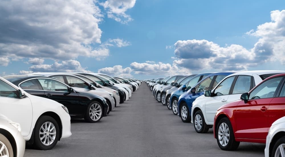 Two rows of cars parked on a cloudy day.