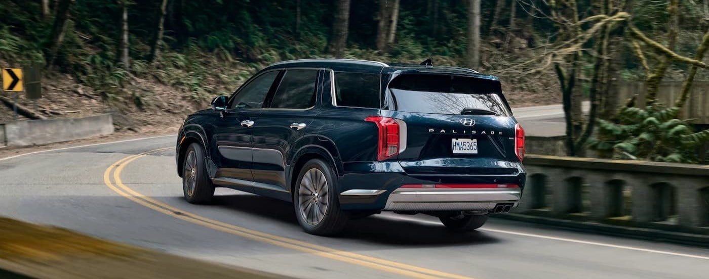 A blue 2025 Hyundai Palisade driving on a highway.