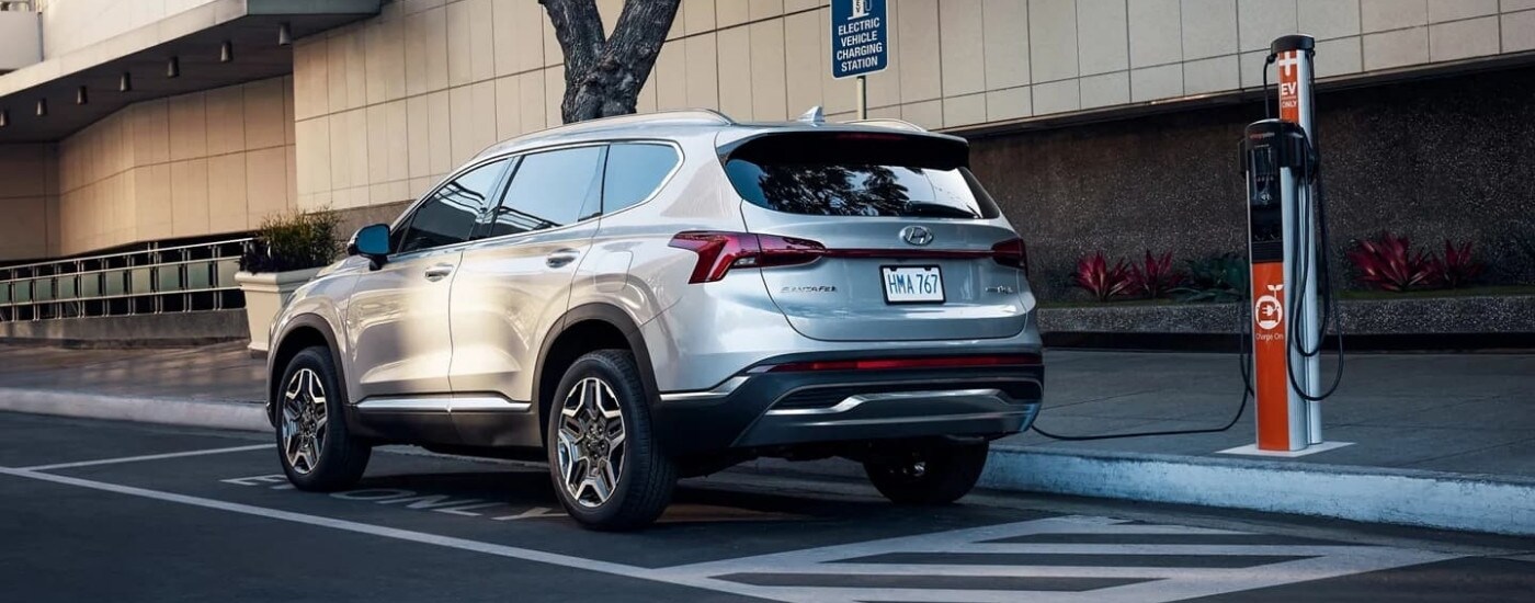 A silver 2023 Hyundai Santa Fe PHEV at a charging station.