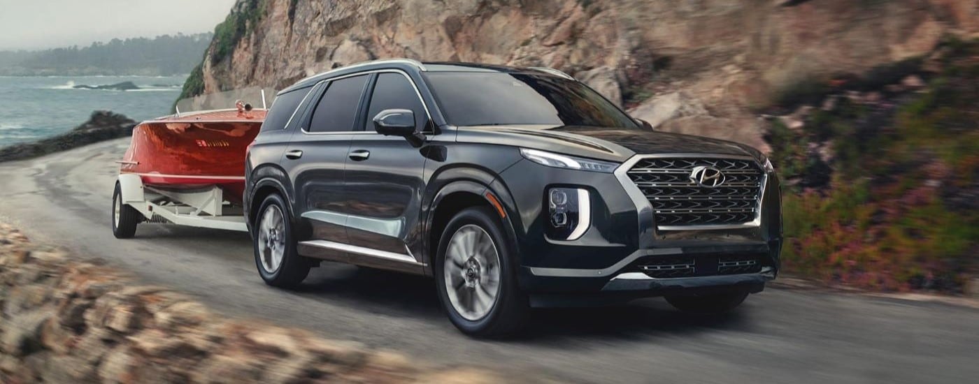 A black 2020 Hyundai Palisade towing a boat around a bend.