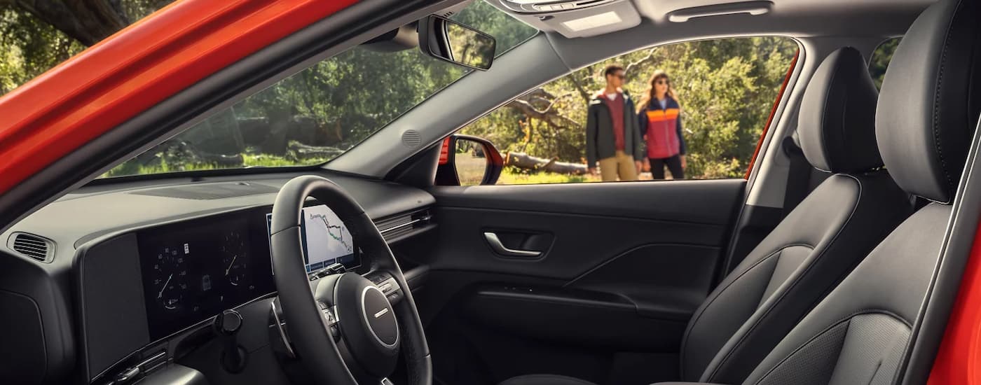 Front seats and dashboard in an orange 2025 Hyundai Kona
