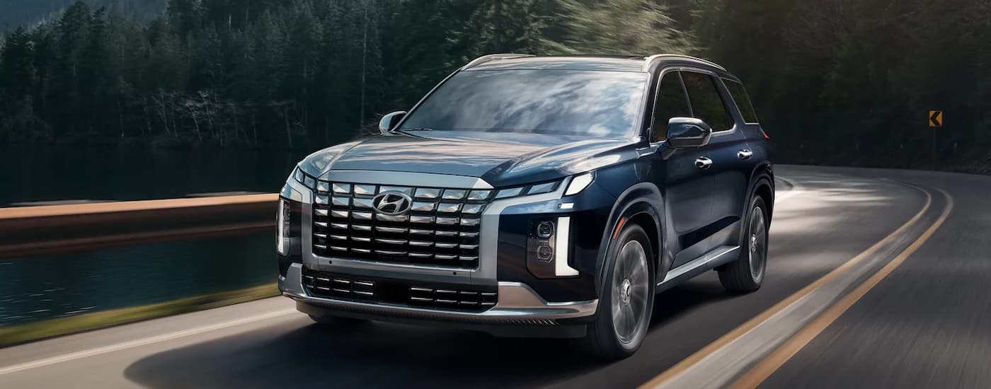 Blue 2025 Hyundai Palisade driving on a winding road