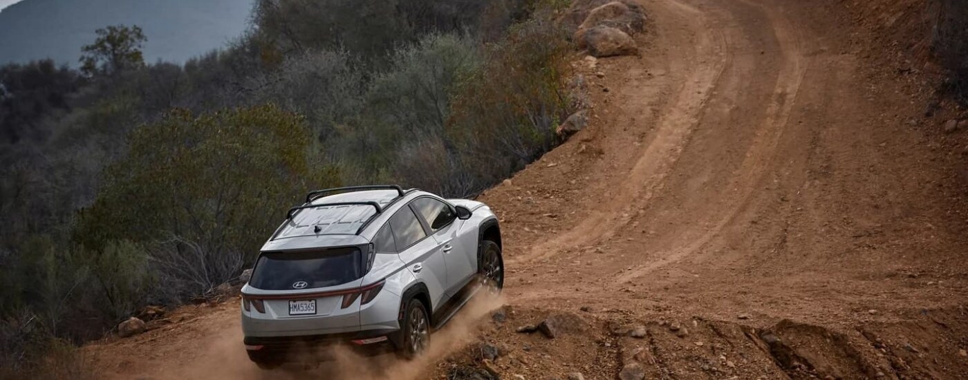 A silver 2023 Hyundai Tucson XRT is driving up a hill.