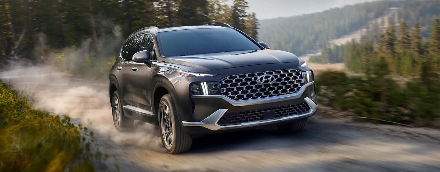 A black 2022 Hyundai Santa Fe driving down a dirt road.