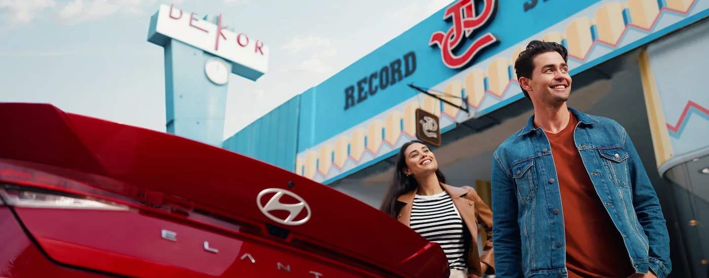 Two people walking near a red 2025 Hyundai Elantra for sale near Indian Trail