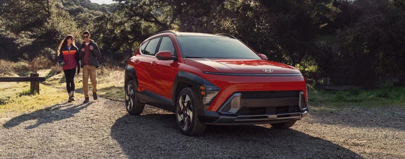 Hikers walking near a red 2024 Hyundai Kona Limited after leaving a Hyundai dealer near Matthews.