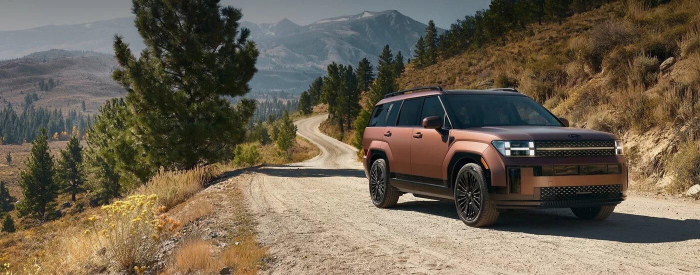 Brown 2025 Hyundai Santa Fe for sale near Matthews test driving on a mountain road.