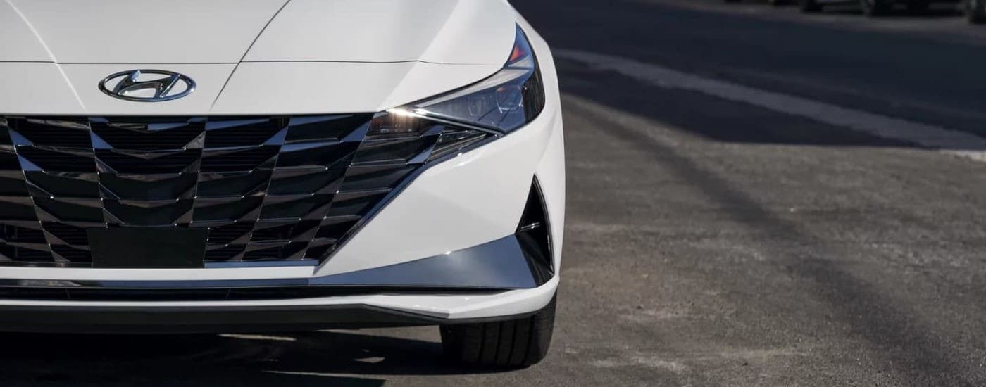 A close-up on the hood of a white 2021 Hyundai Elantra Hybrid leaving a used Hyundai dealer.