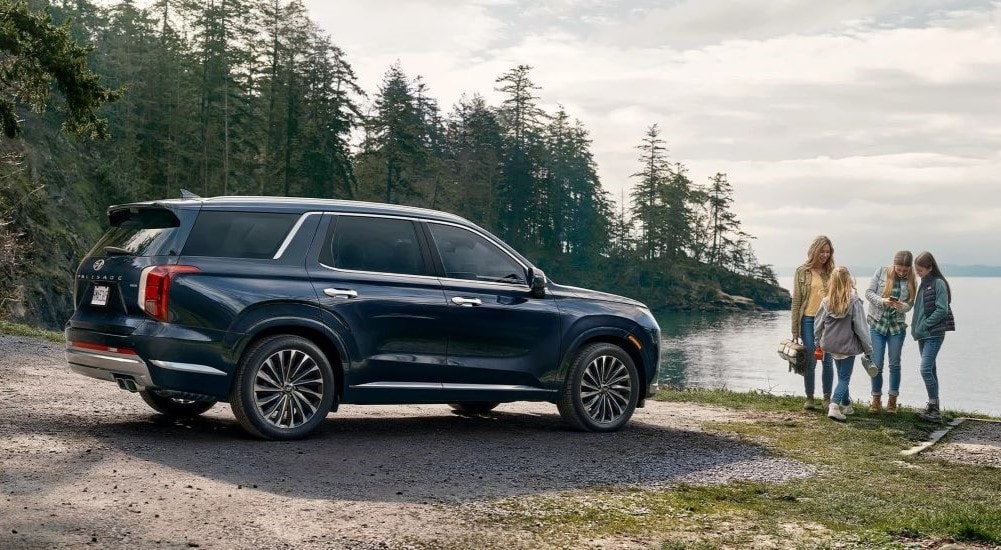 A blue 2023 Hyundai Palisade parked near a lake.