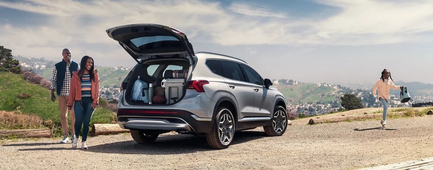 A family near a silver 2023 Hyundai Santa Fe PHEV after leaving a used Hyundai dealer near Matthews.