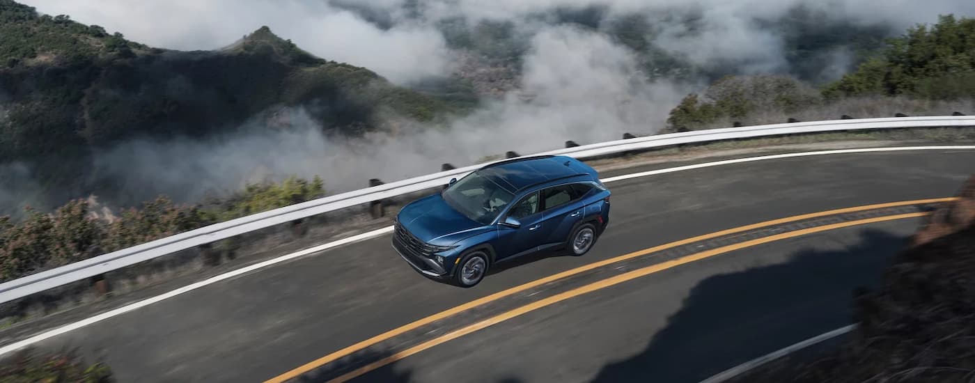Blue 2025 Hyundai Tucson driving on a winding road