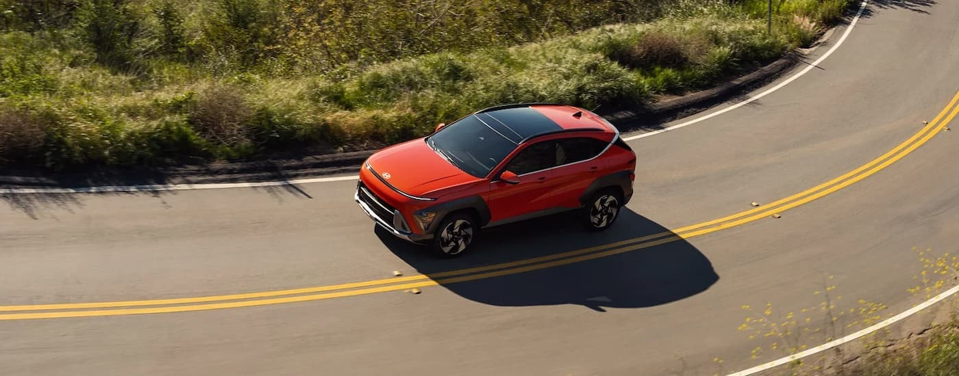Orange 2025 Hyundai Kona for sale driving on a winding road