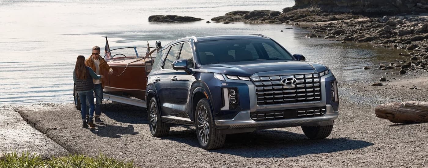 A blue 2025 Hyundai Palisade for sale towing a boat.