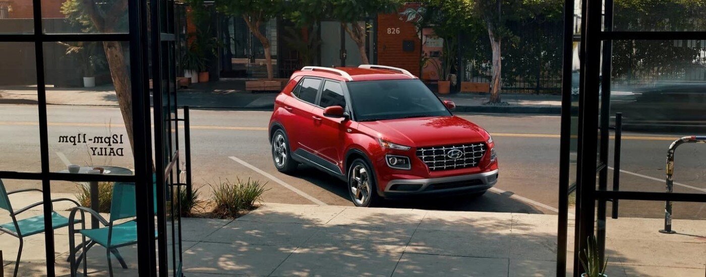 A red 2023 Hyundai Venue SEL parked in front of a shop.