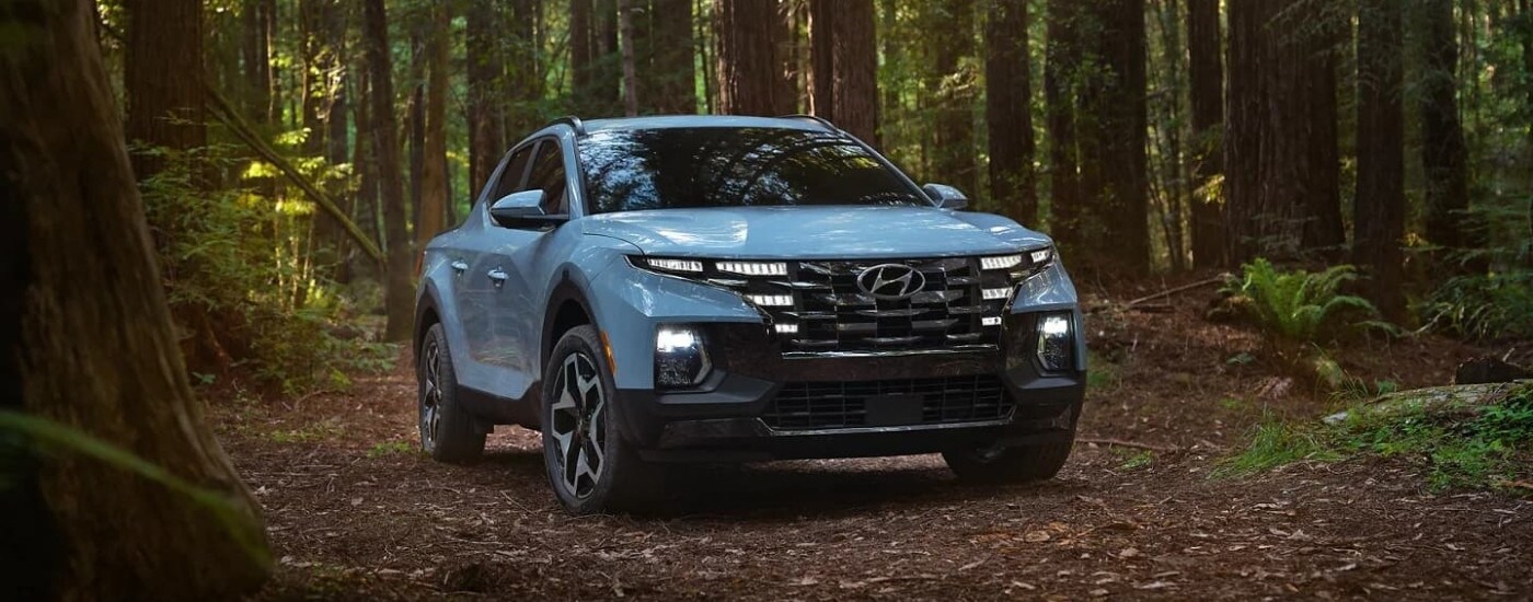 A blue 2022 Hyundai Santa Cruz parked in a forest.