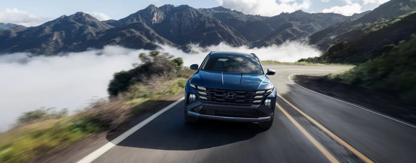A blue 2025 Hyundai Tucson for sale in Monroe driving on a highway.