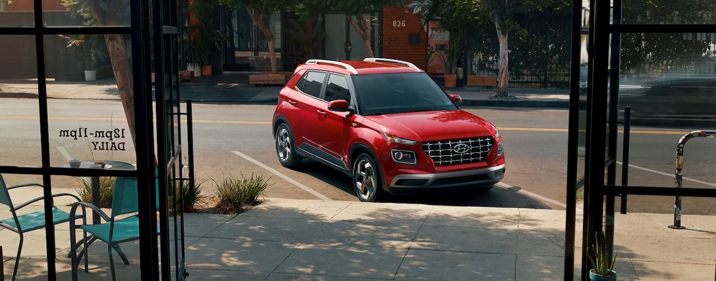 Red 2025 Hyundai Venue parked on the side of a street outside of a cafe