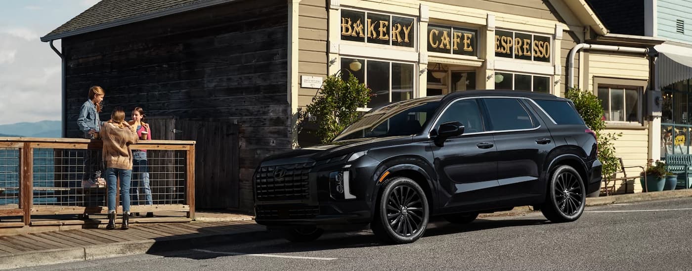 Black 2025 Hyundai Palisade Calligraphy parked on the side of a street near a cafe