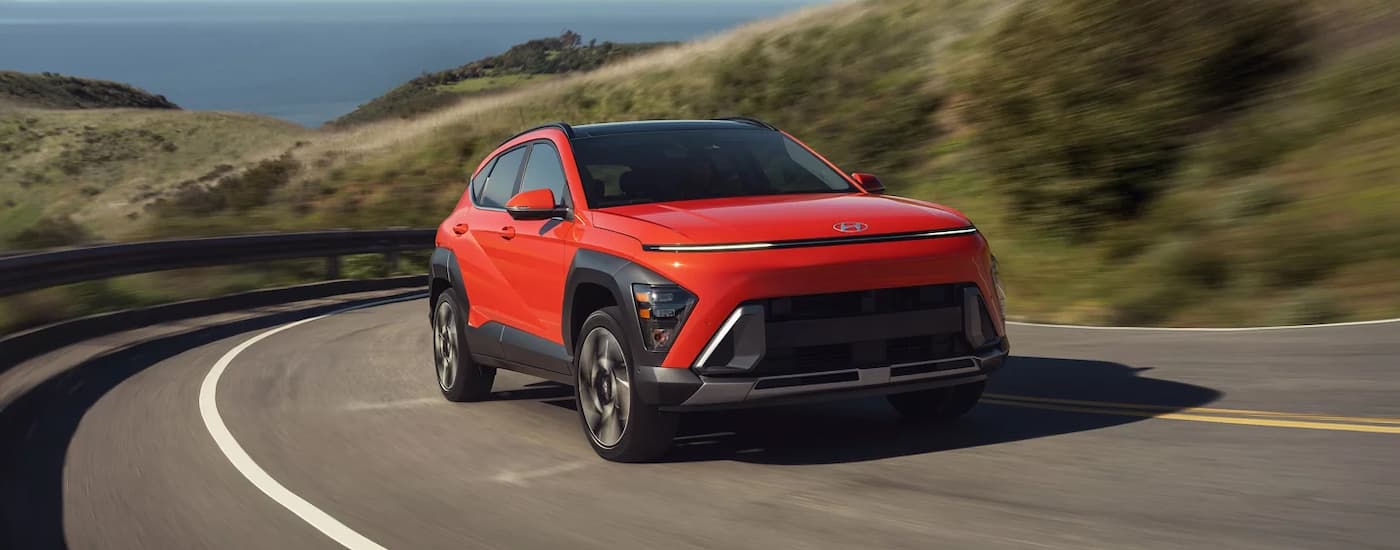Red 2025 Hyundai Kona driving around a bend.