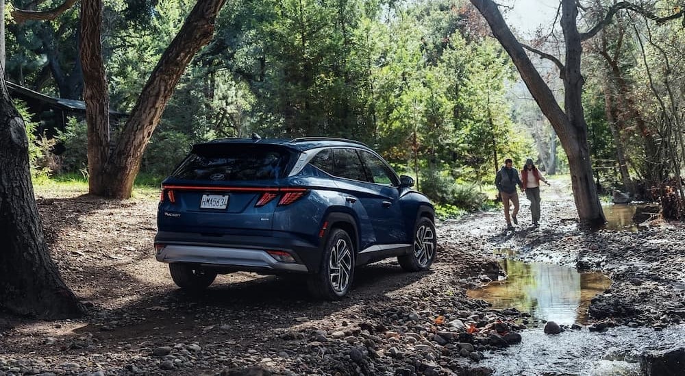 A blue 2025 Hyundai Tucson parked in a forest.