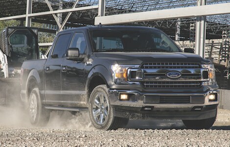 Black Ford F-150 A black Ford F-150 hauling construction equipment a cross a construction site