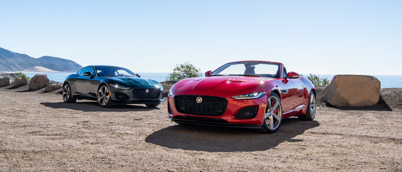 Two 2022 Jaguar F-TYPEs parked on a sandy ocean overlook