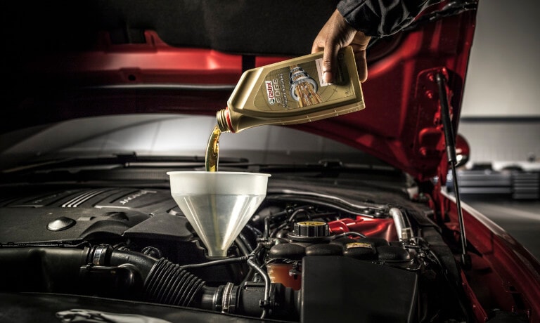 Technician pouring new oil into a car under the hood
