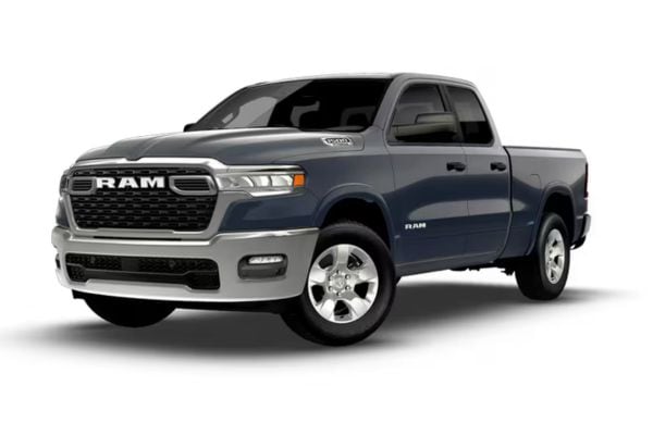 Front three-quarter view of a dark slate blue 2026 RAM 1500 Big Horn family truck featuring chrome bumpers and chrome front grille accents.