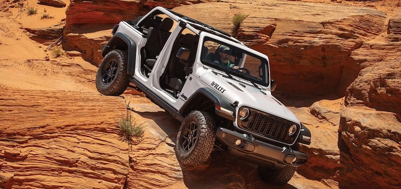 2026 Jeep Wrangler Willys climbing rocky terrain demonstrating Jeep trail capability