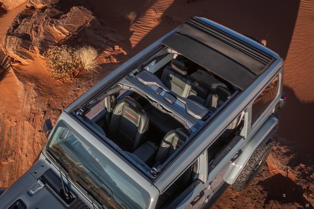 Available Sky One-Touch Power Top on a Jeep Wrangler shown open from an overhead view in the desert