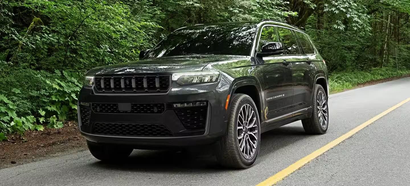 2026 Jeep Grand Cherokee driving on a tree-lined road
