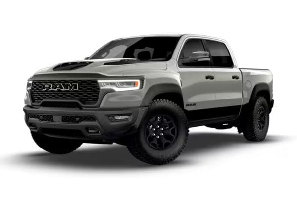 Front three-quarter view of a silver 2026 RAM 1500 Laramie premium luxury truck featuring a sport performance hood and dark off-road styling accents.