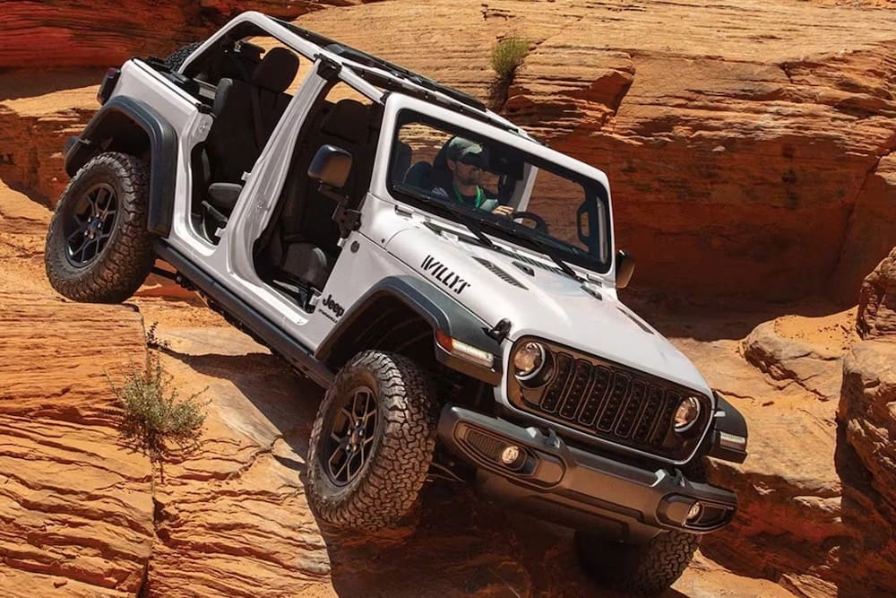 2026 Jeep Wrangler Willys climbing red rock terrain with removable doors showcasing off-road capability