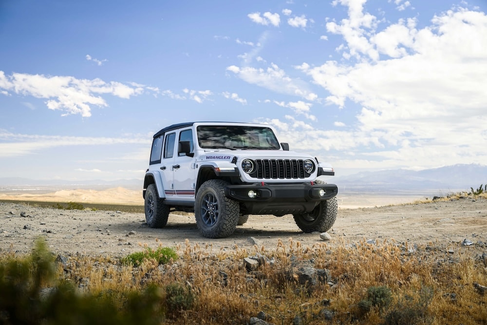 2026 Jeep Wrangler parked on a scenic overlook highlighting its iconic seven-slot grille and off-road capability