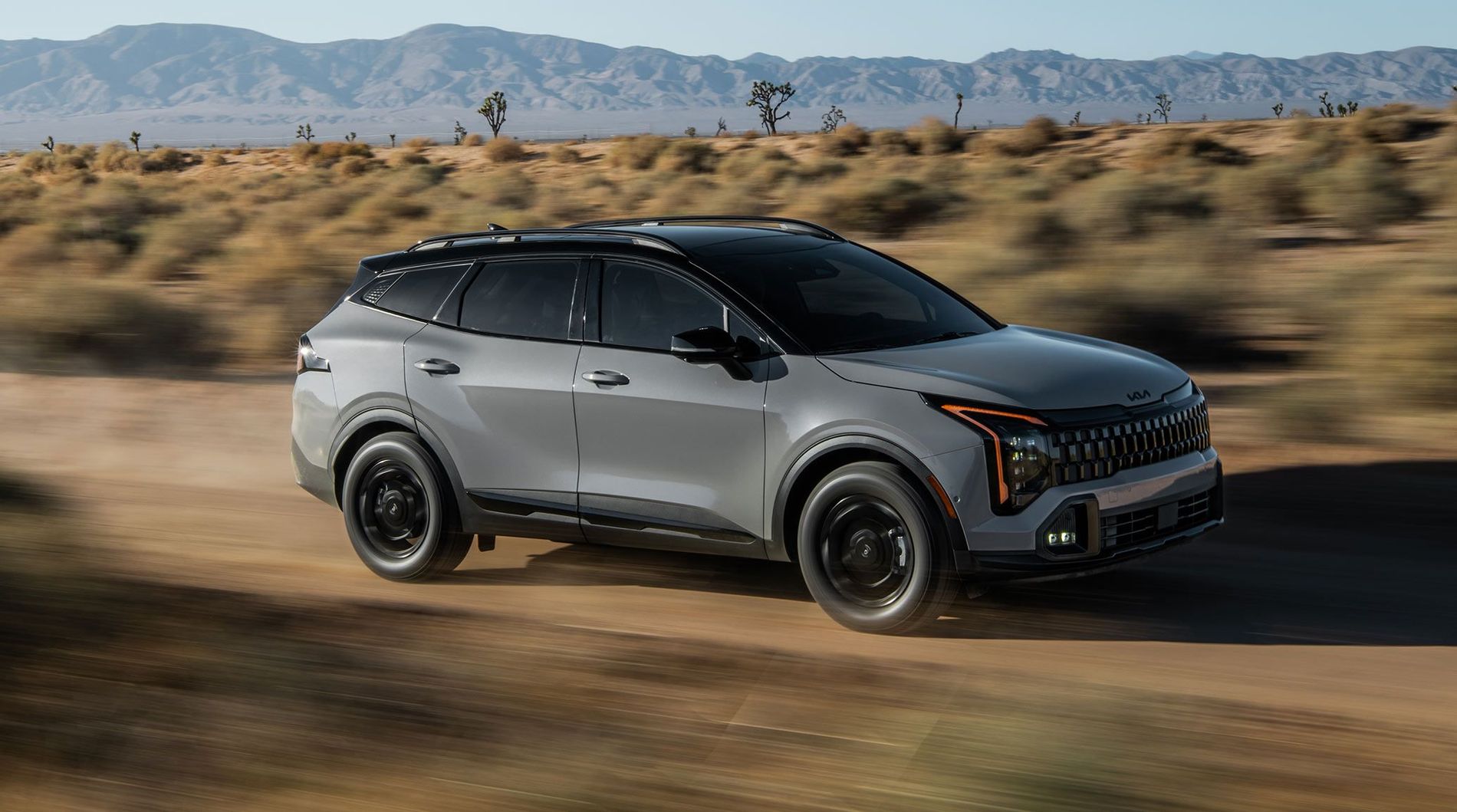 Kia Sportage gris visto desde el frente y el costado en un camino del desierto