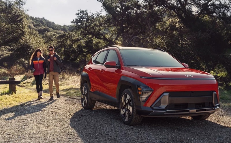 Hyundai Kona parked in the woods with couple walking up to it