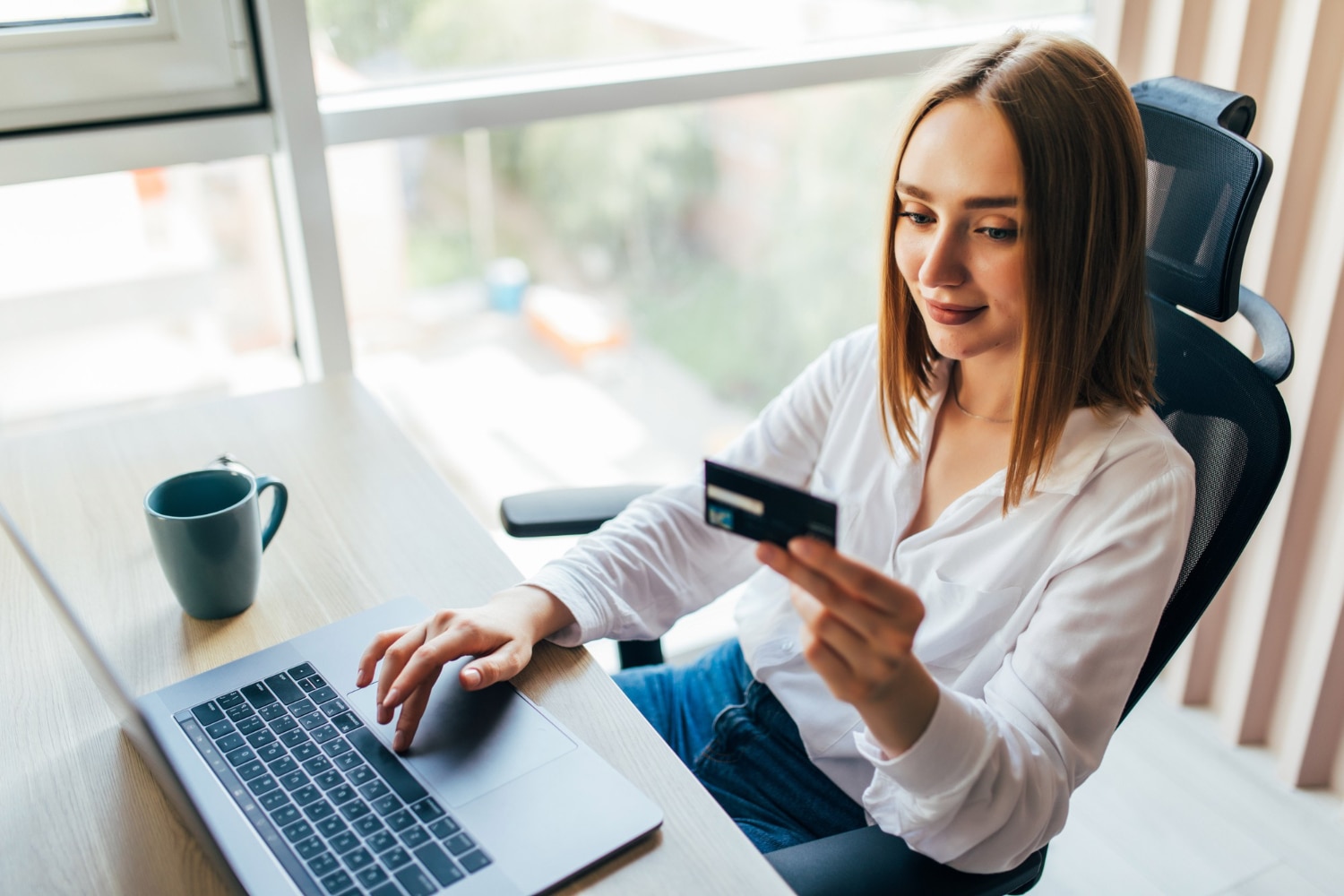 Woman holding credit card while on laptop using online finance tools