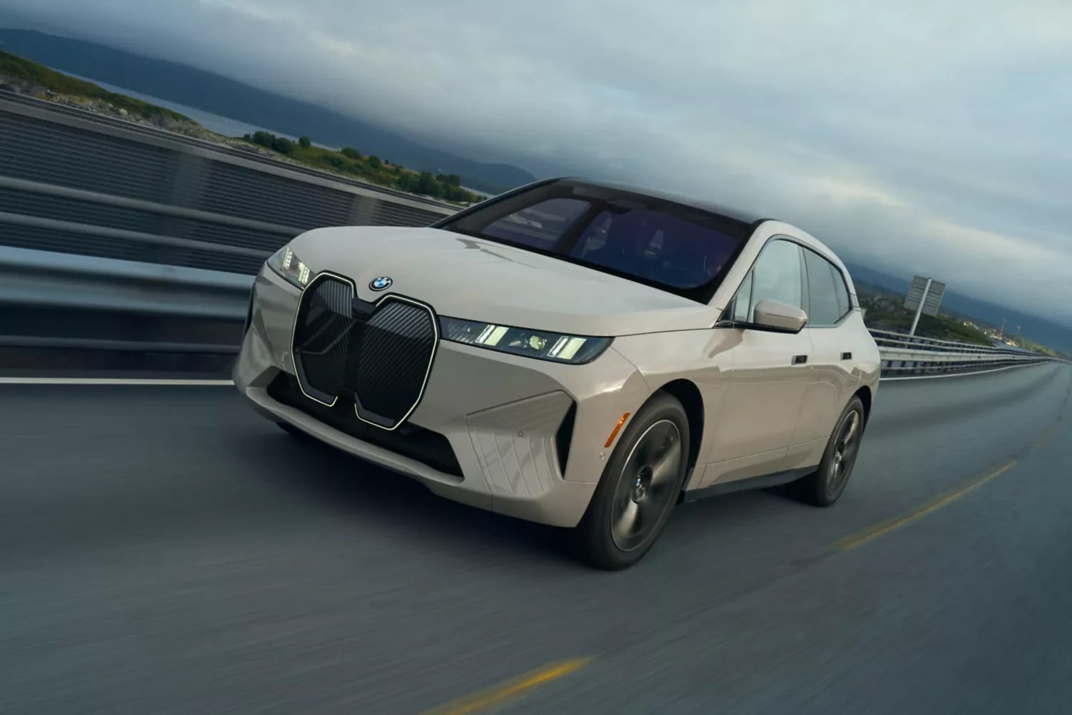 A cream-colored BMW iX driving down the highway A cream-colored BMW iX driving down the highway
