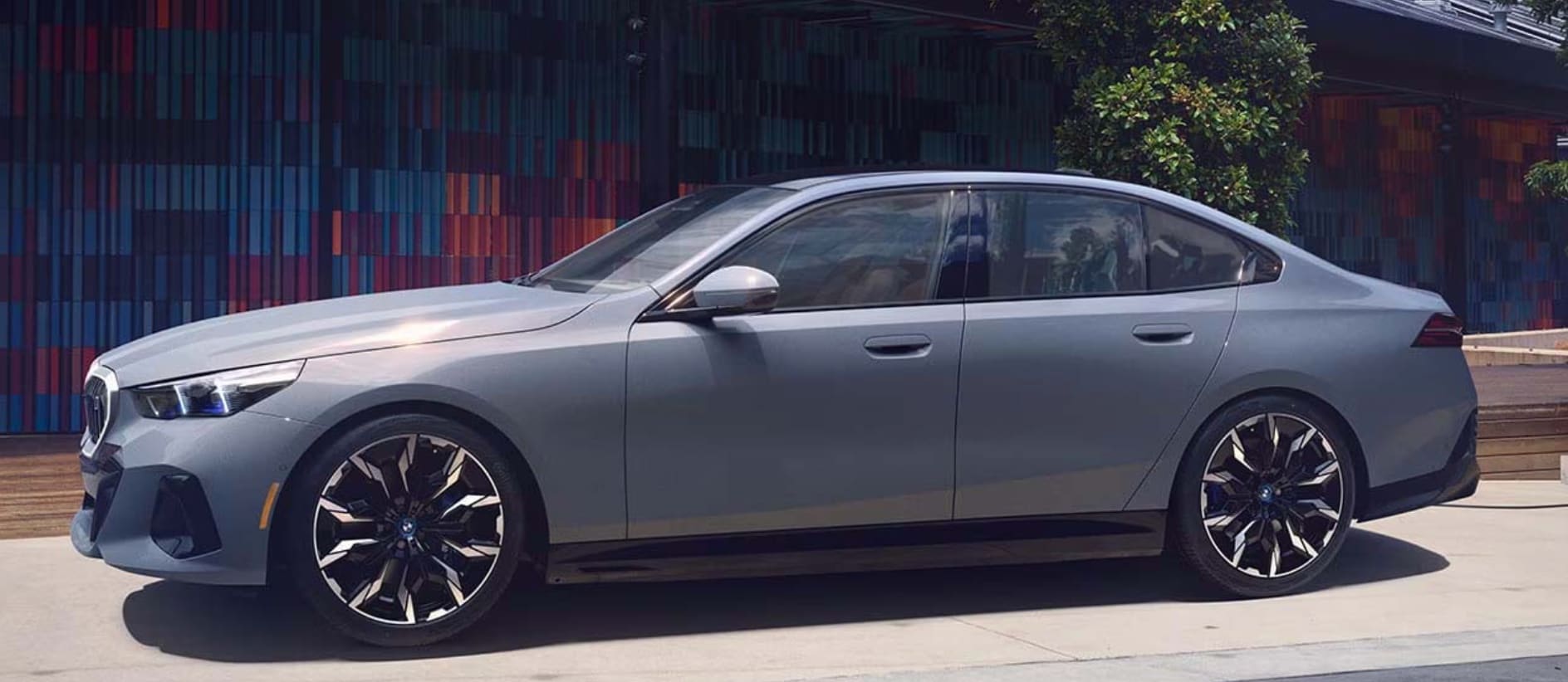 A gray BMW i5 in profile, parked on the street.